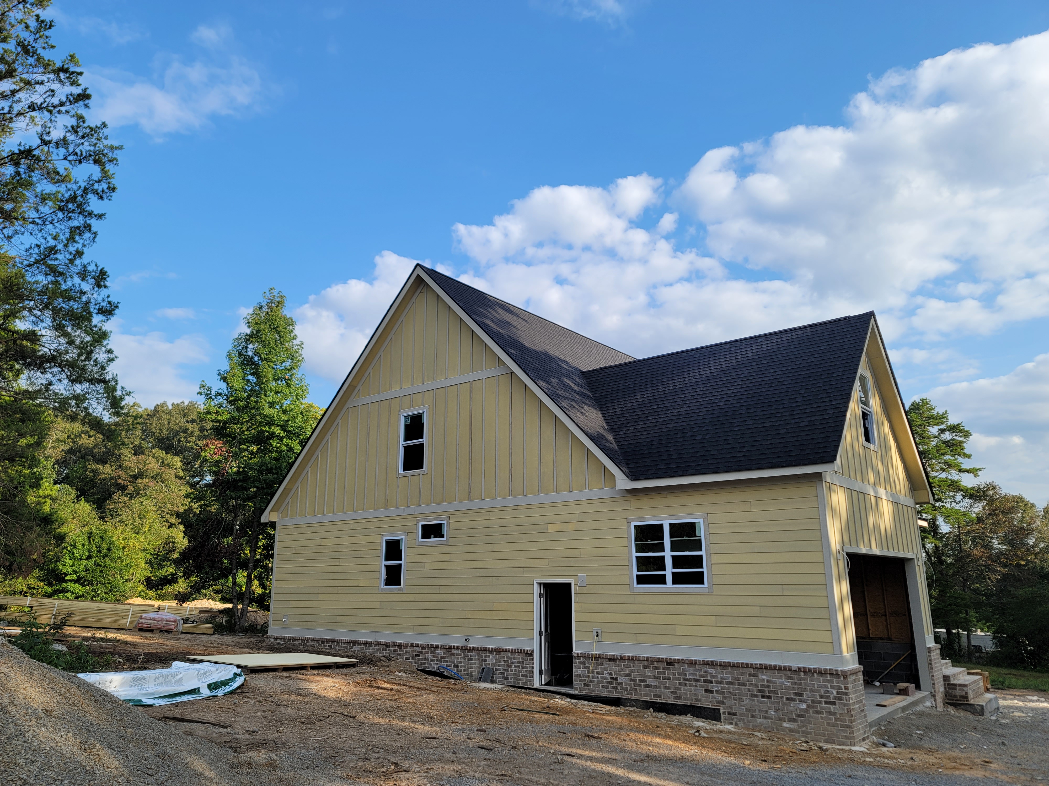 New home construction with yellow siding and brick skirt
