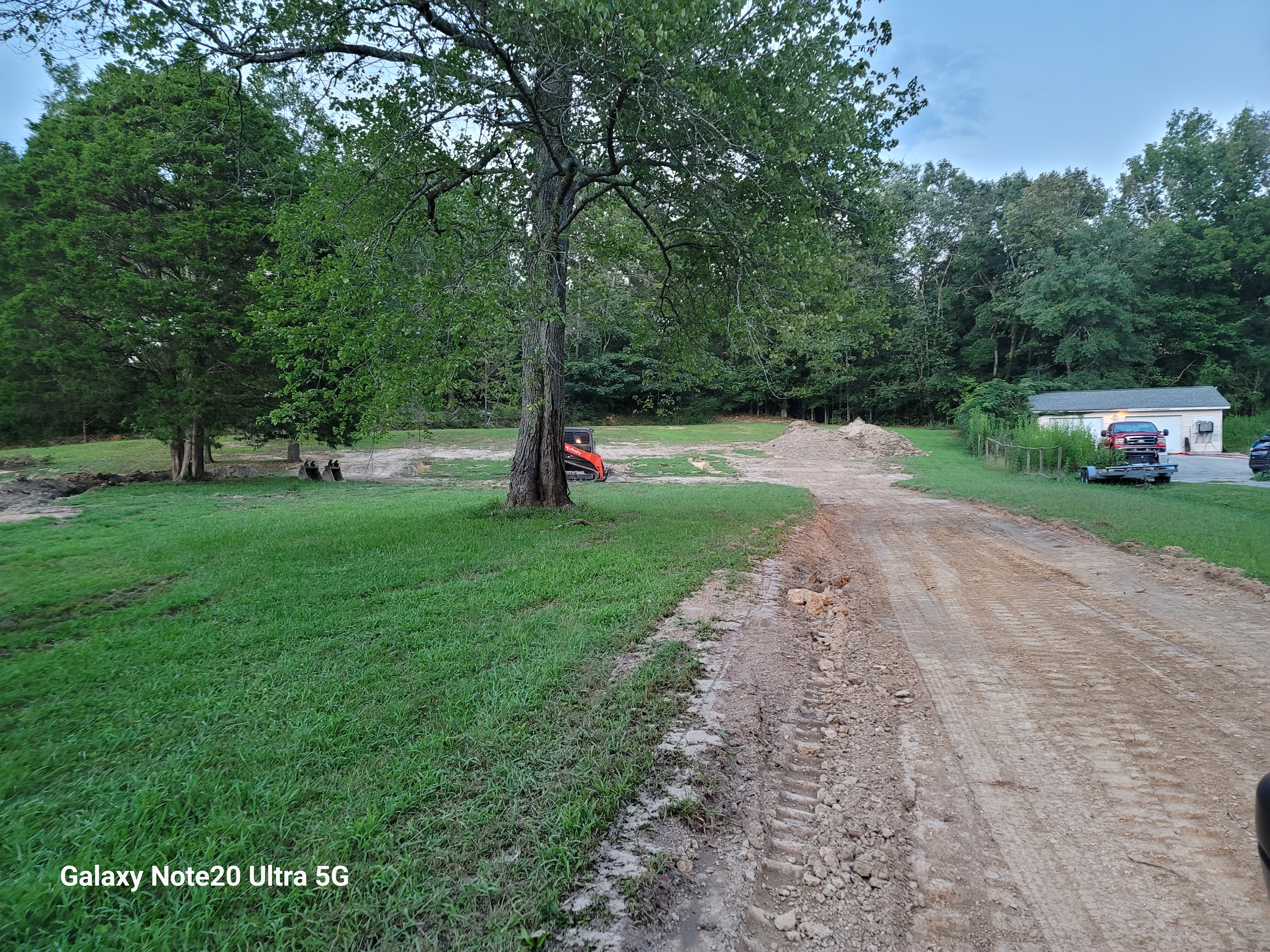 Skid steer grading a dirt driveway